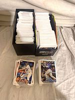 Two storage boxes filled with 2023 Topps baseball cards and two stacks of loose cards in front