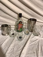 All seven items grouped: metal tankard, cocktail shaker base, decorative bottle, five assorted glasses