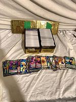 Stacks of Dragon Ball Super trading cards in two gold metal tins with several cards spread in front