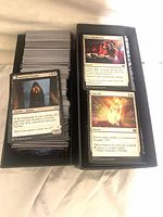Open card box with two rows of stacked MTG cards showing Innocent Traveler and Sanctify
