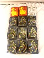 All twelve sealed packs laid out: two Pikachu, one Arceus, nine Lucario designs