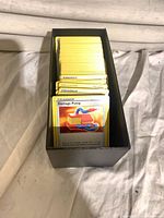 Black storage box holding yellow-border Pokémon Trainer cards, top card Damage Pump visible