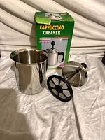 All components laid out: stainless pitcher body, plunger lid with mesh, plastic disc, box