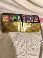Two gold embossed Yu-Gi-Oh! tins filled with assorted cards