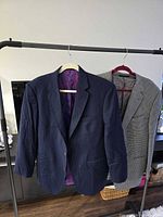 Front view of both blazers hanging on rack