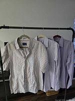 Three shirts on hanger showing overall view: plaid short-sleeve, two lavender long-sleeve