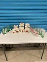 Complete lot on table showing canisters, mugs, green tumblers and clear glasses