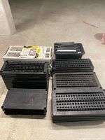 Stack of black vented resin shelves, gray shelf, bin of support poles