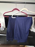Full view of navy trousers on hanger showing color and cuffed hems