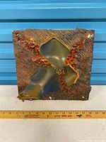 Front view of square ceramic relief panel showing full design and ruler for scale