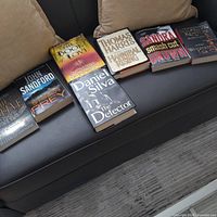 All seven novels arranged on sofa and rug