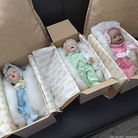 Overview of three dolls in boxes with packing and tissue