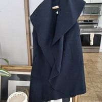 Full view of navy blue sleeveless shawl jacket hanging
