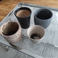 Four assorted flower pots on glass table, top view