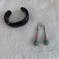 onyx cuff bracelet beside pair of turquoise drop earrings