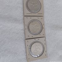 Three 1964 Kennedy half dollars in flips aligned vertically