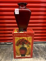 Front view of red glass vase on top of original box