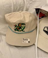 Beige snapback with toucan embroidery and turquoise rope on brim