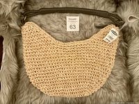 Full view of woven shoulder bag with handle and tag visible