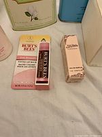 Front view of lip balm and perfume miniature with background tins
