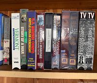 Shelf with assorted VHS including Story of a War, U.S. Marine Corps Battle Color Ceremony, The Last Days of WWII, The Three Stooges