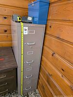 Full view of beige four-drawer filing cabinet beside desk