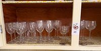 Cabinet shelf showing majority of clear stemmed glasses
