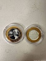 Front and back of the Planet Hollywood ten-dollar gaming token in capsules