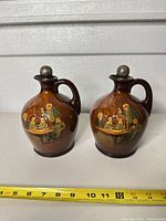 Front view of both Royal Doulton Pickwick jugs with tape showing ~7 in height