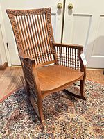Full view of carved oak rocking chair on rug
