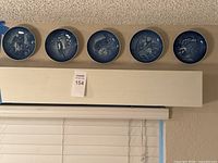 Five blue ceramic plates with animal scenes displayed in a row