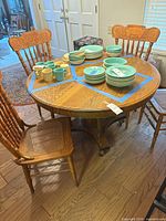 Round oak pedestal table with three chairs visible and dishware on top