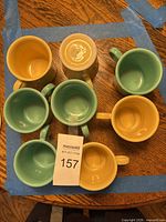 Top view of eight Fiesta mugs showing interior colors (4 turquoise-green, 4 yellow)