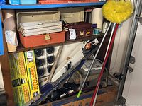 Two shelves showing grow light box, tackle box, duster, projection screen and assorted supplies