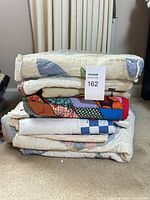 Stack of six folded quilts with variety of patterns