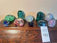 Full view of all glass eggs, insulators, paperweights, bowl, saucer and marble arranged on wooden shelf