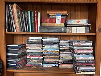 Upper bookcase shelf with books and large stacks of DVD cases