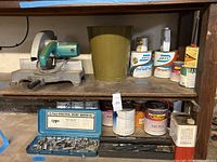 Shelf with Makita miter saw, waste bin and multiple paint/stain cans