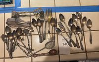 Overhead view of mixed vintage silver plate flatware pieces laid out on tile counter