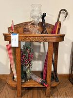 Full view of oak umbrella stand with umbrellas, canes, glass items displayed