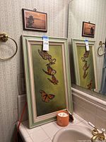 Butterfly painting, plaque, candle on bathroom counter