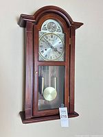 Full view of wooden Parliament pendulum wall clock hanging on wall