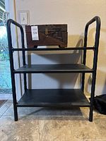 Front view of 3-tier metal shelf with carved wood box on top