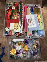 Three bins filled with gift wrap rolls, ribbons, bows, bags