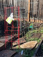 Red square folding cage alongside round silver cages in garden setting