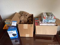 Overall lot: two boxes containing teddy bears, stack of jigsaw puzzles, upright maps