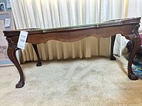 Full view of carved coffee table showing glass top and legs