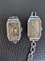 Two vintage rectangular wristwatches side by side on leather surface