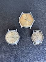 Group shot of all three wristwatches showing brands, dial conditions and absence of straps