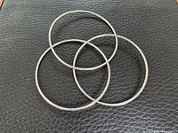 Three silver bangles laid flat on textured surface